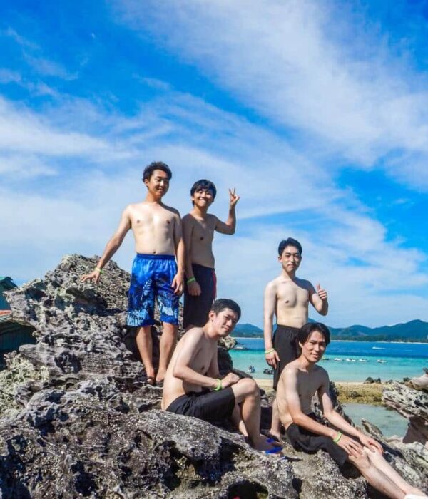 khai-island-five-guests-seaside-rocks カイ島の海沿いの岩場で並んで写真を撮る5名のお客様