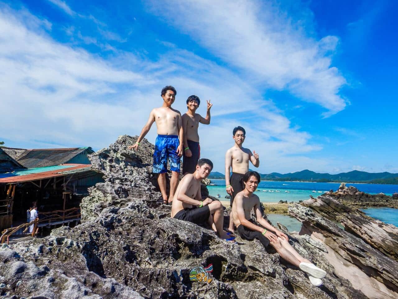 カイ島の海沿いの岩場で並んで写真を撮る5名のお客様